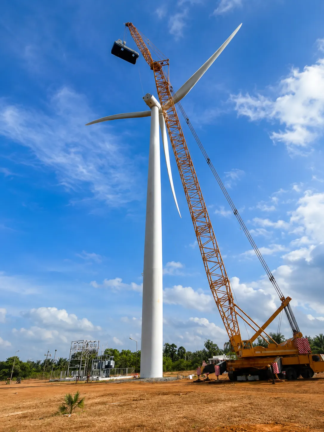 Crane lifting nacelle component onto turbine