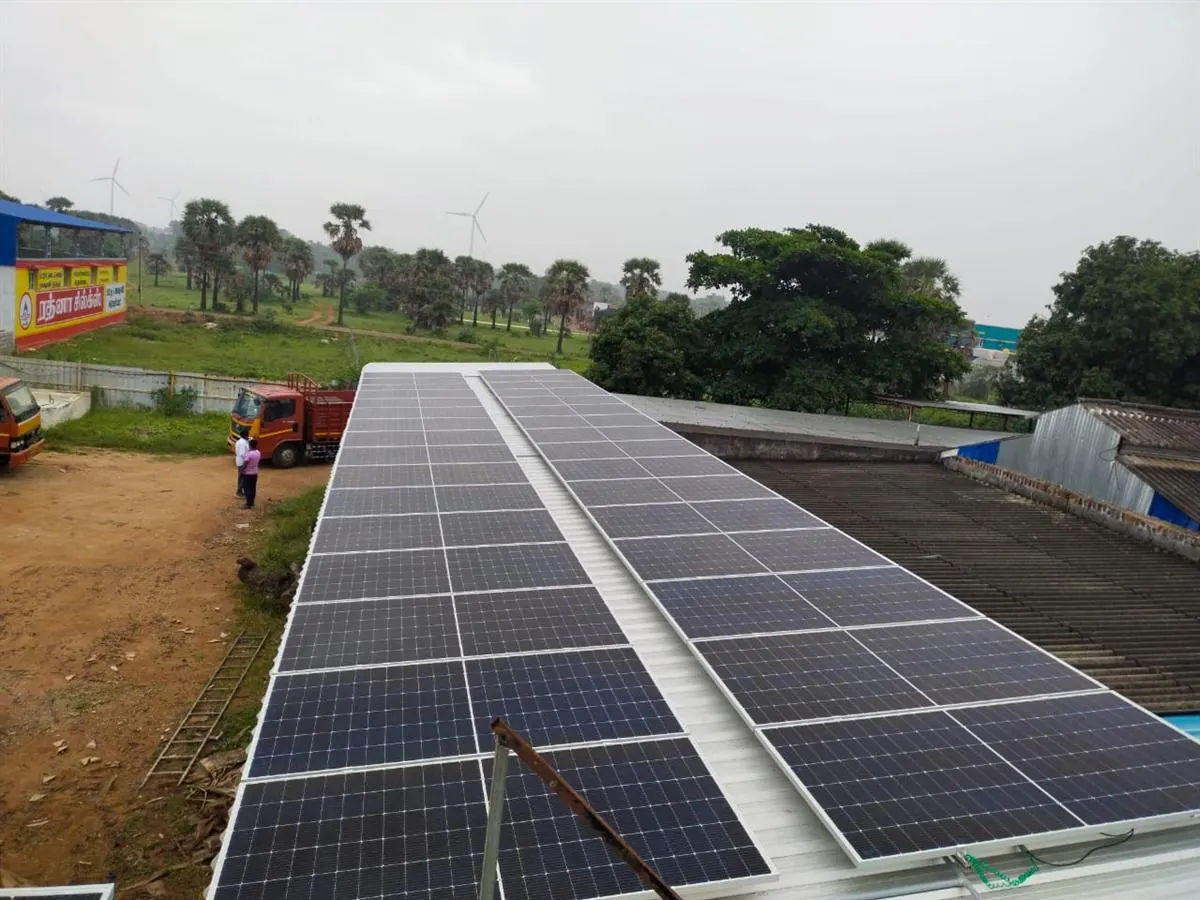 Rooftop solar installation with wind turbines in the background